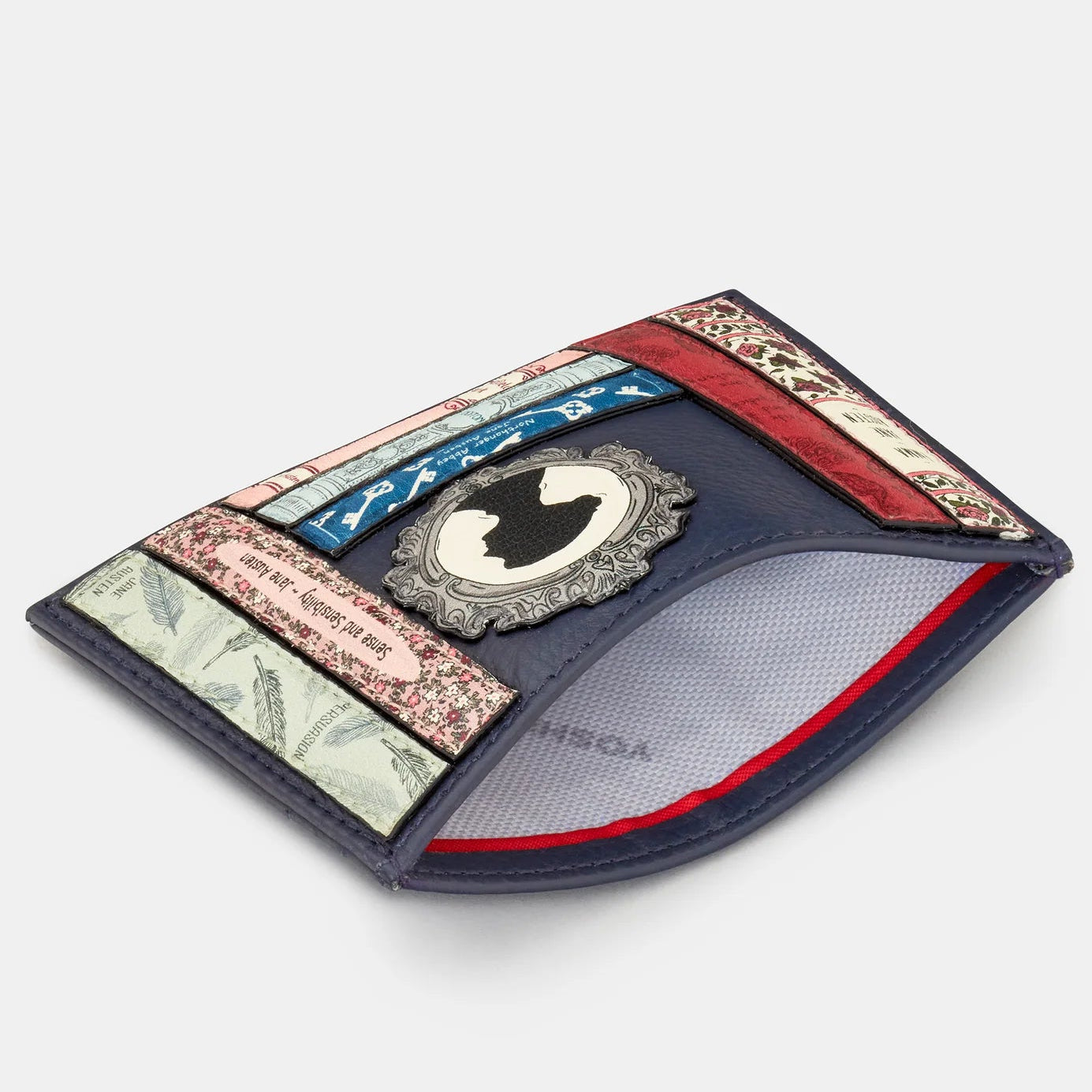Angled open view of Jane Austen navy leather card holder revealing central slip pocket with red lining and stitched book-spine detail; slim RFID wallet.