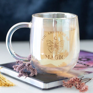 You Are Made of Magic Iridescent Double Walled Glass Mug filled with tea, featuring gold butterfly design and glowing pearlescent finish.