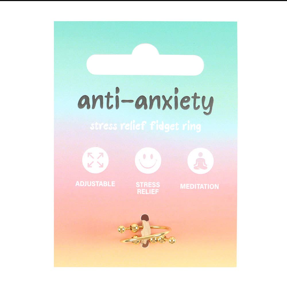 Front view of the anti-anxiety fidget ring packaging card featuring a beautiful gradient background transitioning from turquoise at the top through soft pink to warm orange at the bottom. The card displays 'anti-anxiety stress relief fidget ring' text in dark lettering, with three illustrated icons below showing adjustable fit, stress relief, and meditation benefits. At the bottom of the card, the gold-toned ring with decorative rotating beads is displayed prominently against the colourful backdrop.