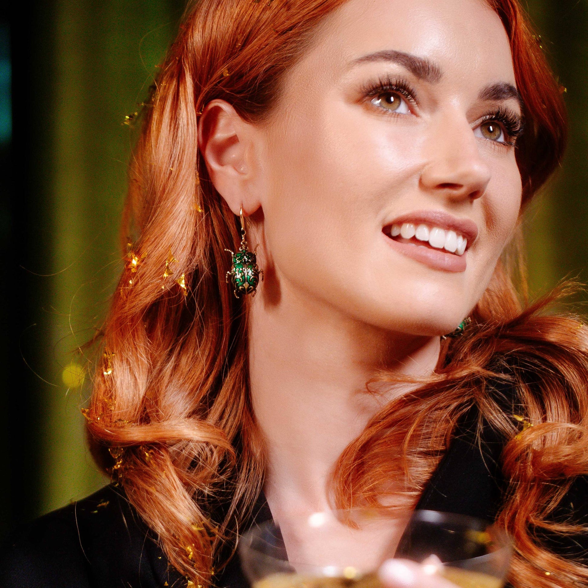 Close-up of Antique Beetle Drop Earring in emerald green enamel and antique gold worn by a model.