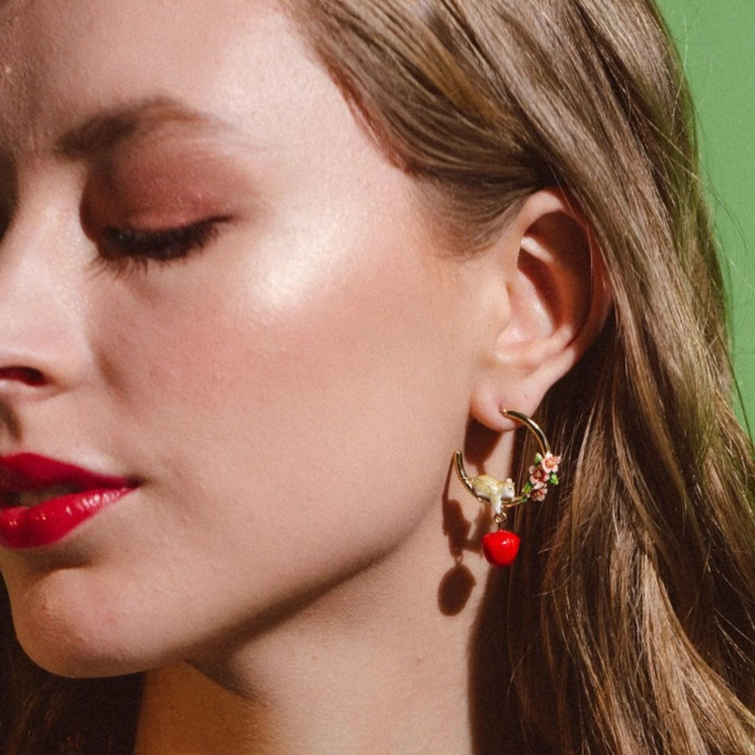 Portrait of model wearing Apple Blossom & Mouse Hoop Earrings with hand-painted blossoms and dangling red apple charm.
