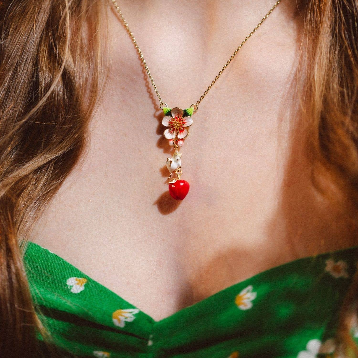 Model wearing Apple & Mouse Blossom Pendant with green floral dress, showing pendant detail.