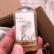 Silver enamel daisy earrings on message card inside glass terrarium held in hand