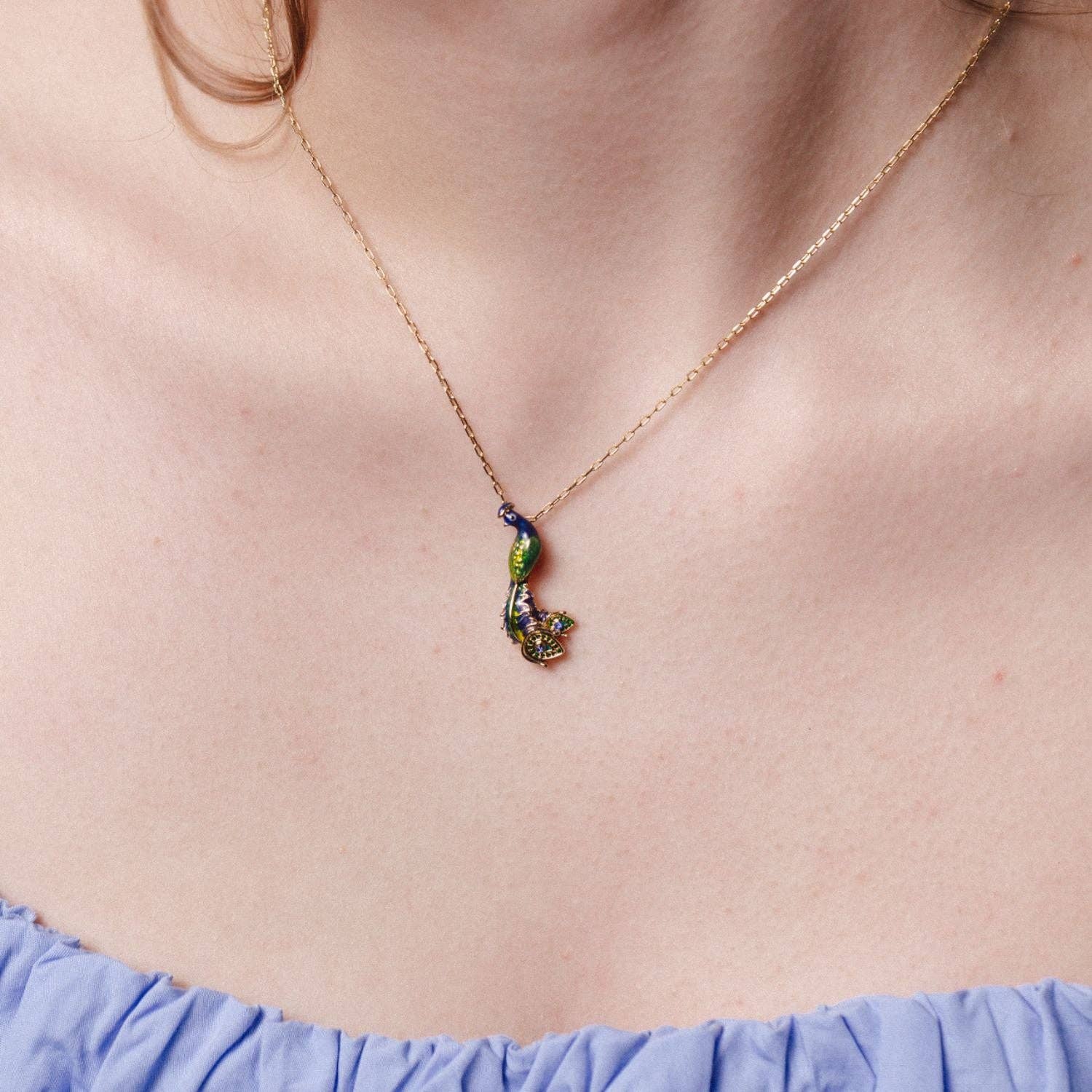 Model in blue top wearing peacock pendant necklace showing how it sits on neckline