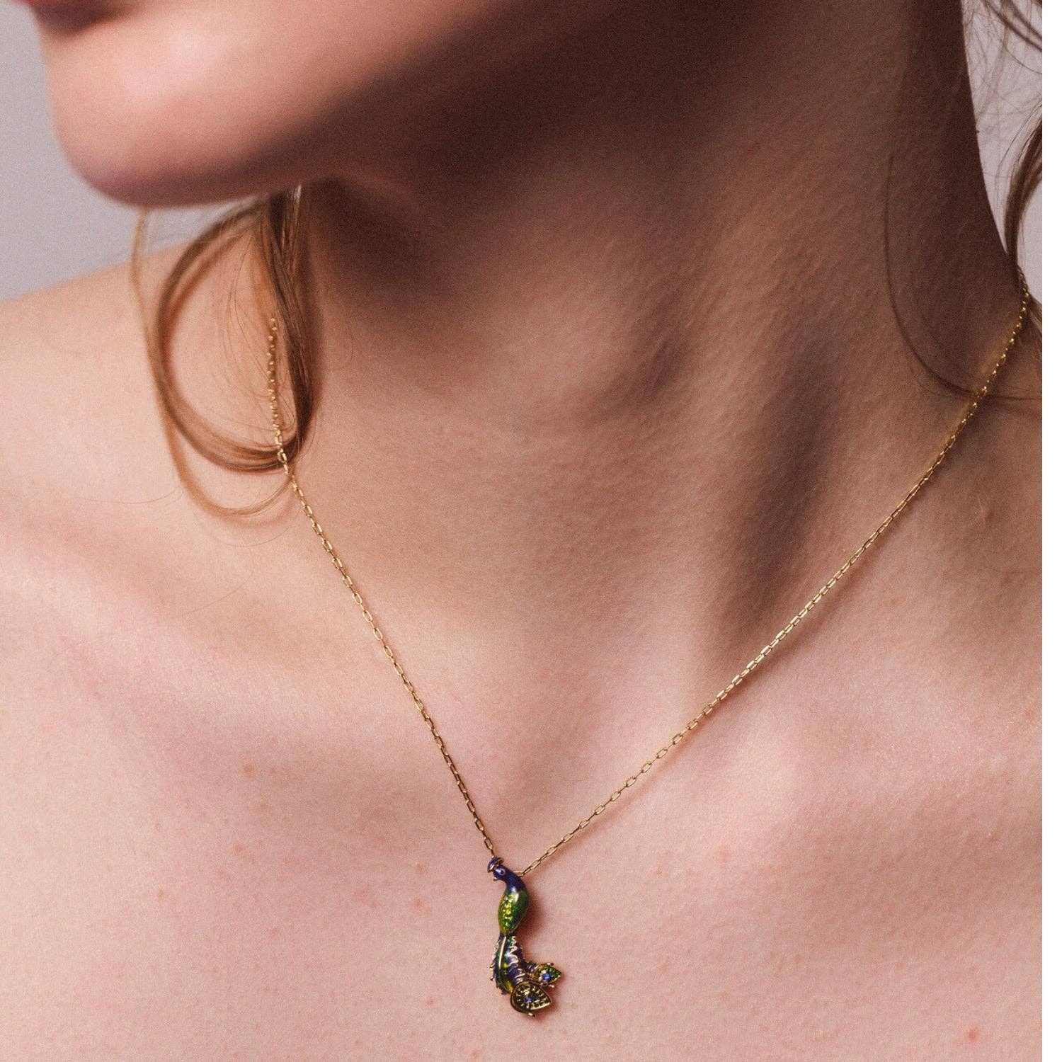 Model wearing peacock pendant necklace with gold chain showing how it looks when worn