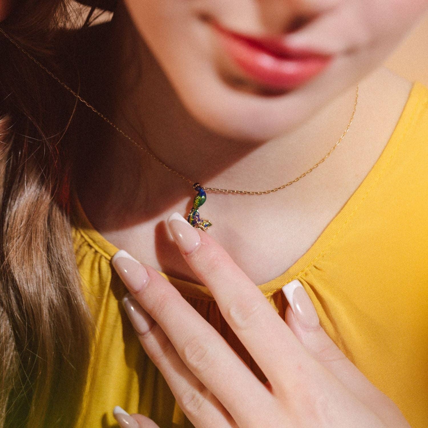 Model in yellow top wearing peacock pendant necklace in lifestyle photo
