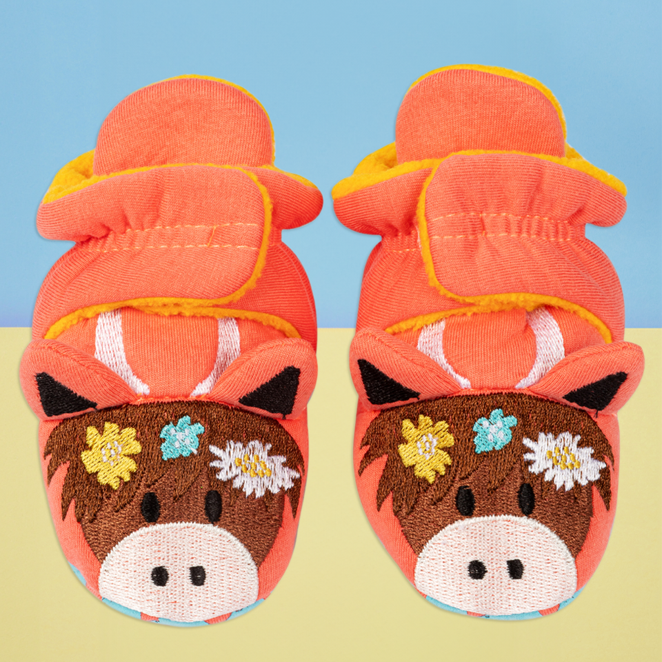 Pair of Bonnie highland cow booties front view on pastel background