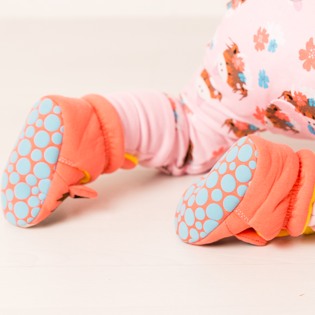 Baby crawling in Bonnie highland cow booties, lifestyle shot