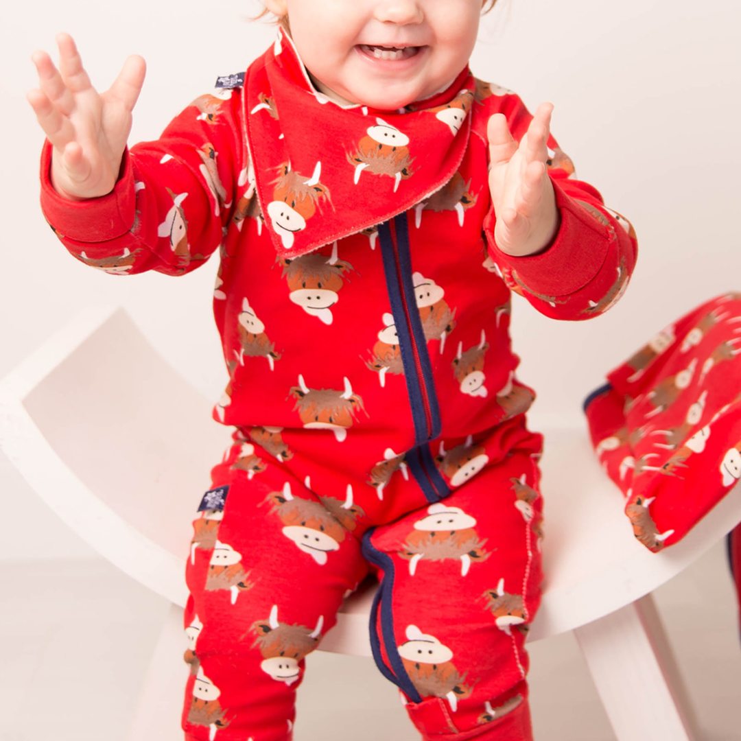 Close-up of baby wearing red highland cow romper, upper body