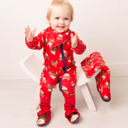 Smiling baby standing in red highland cow zip-up romper