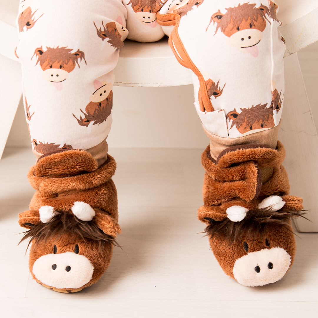 Baby feet wearing brown fleece highland cow booties