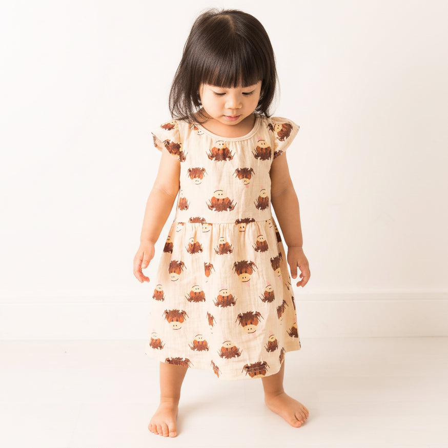 Girl wearing cream highland cow dress with flutter sleeves