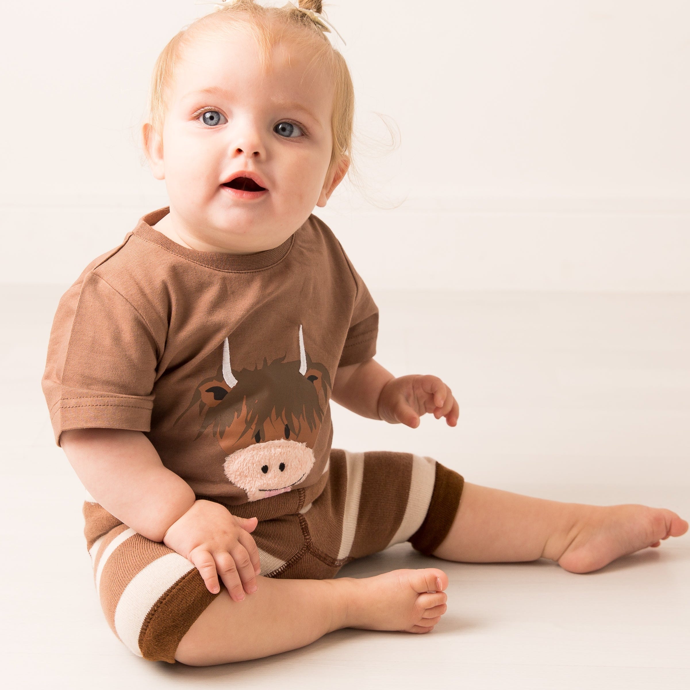 Baby wearing brown highland cow t-shirt with striped shorts