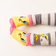 Tweety Bird baby socks on little feet - close-up on cream background