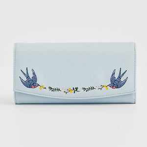 Light blue foldover purse with embroidered birds and floral garland.