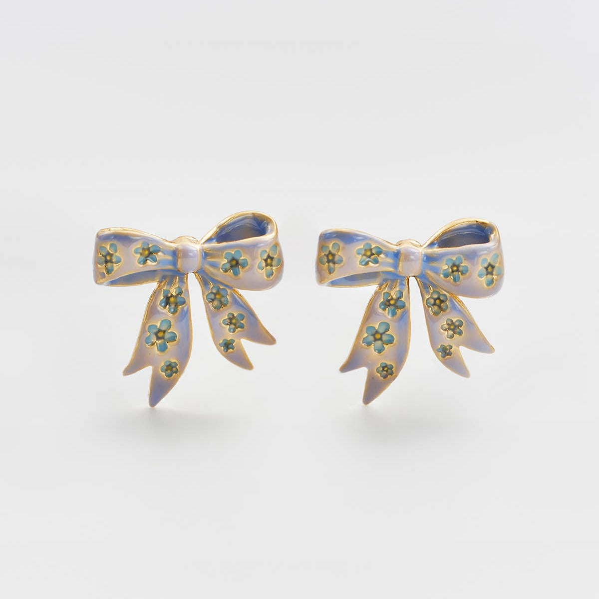Bow stud earrings in gold with blue enamel detailing on white background