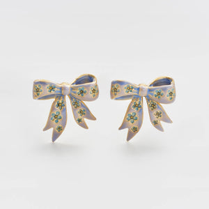Bow stud earrings in gold with blue enamel detailing on white background