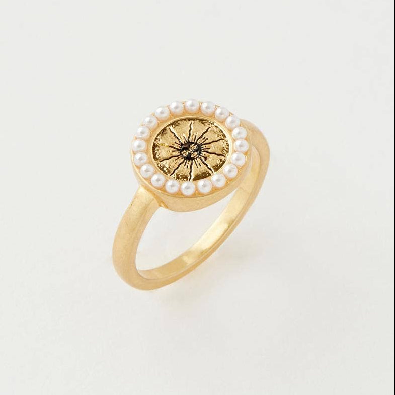 Celestial Ring side view showing gold band and pearl-bordered sun charm on grey background