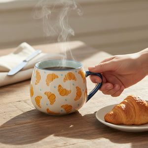 Cream ceramic mug with golden croissant pattern blue dots and dark blue handle