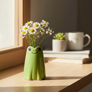 Adorable green ceramic frog mini vase holding white daisies and baby's breath flowers on a wooden surface