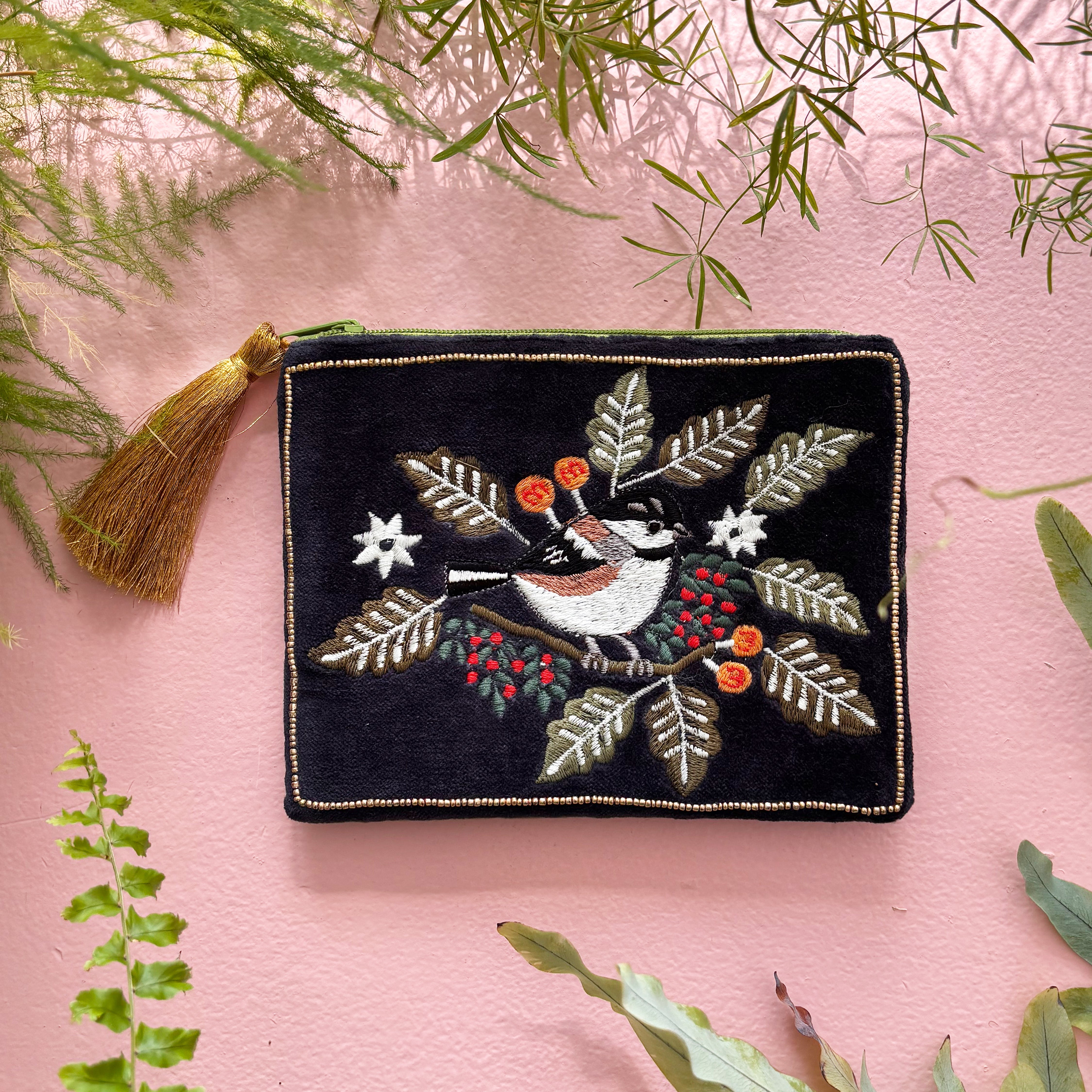 Embroidered bird pouch front view with gold tassel on pink background
