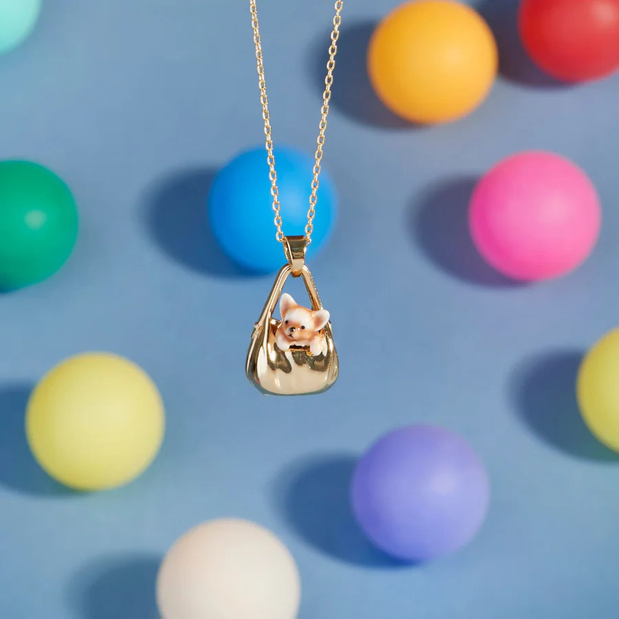 Dog in a Bag Pendant displayed against colourful background balls, highlighting its whimsical design.