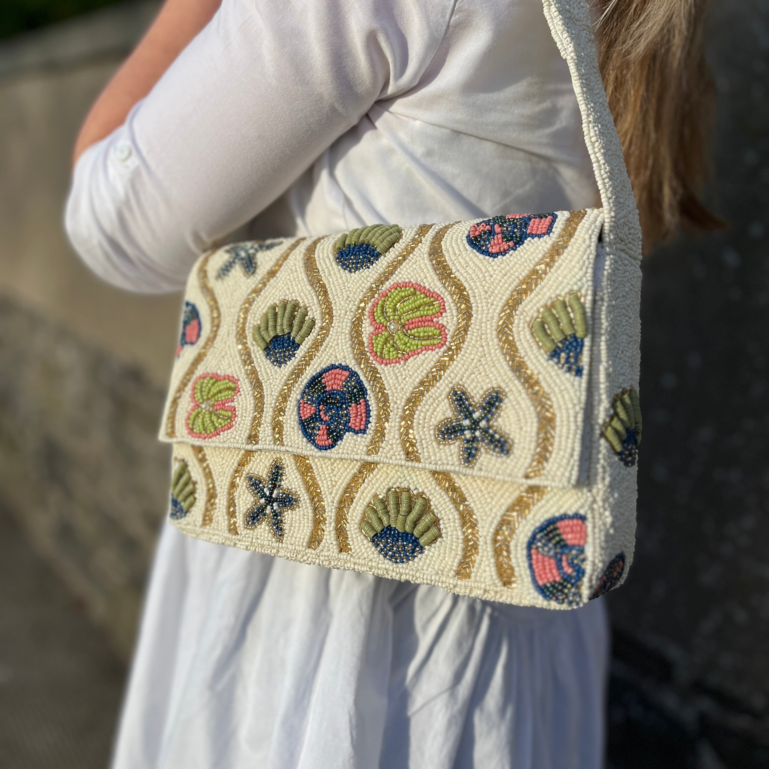 Shell beaded shoulder bag in cream with seashell motifs worn