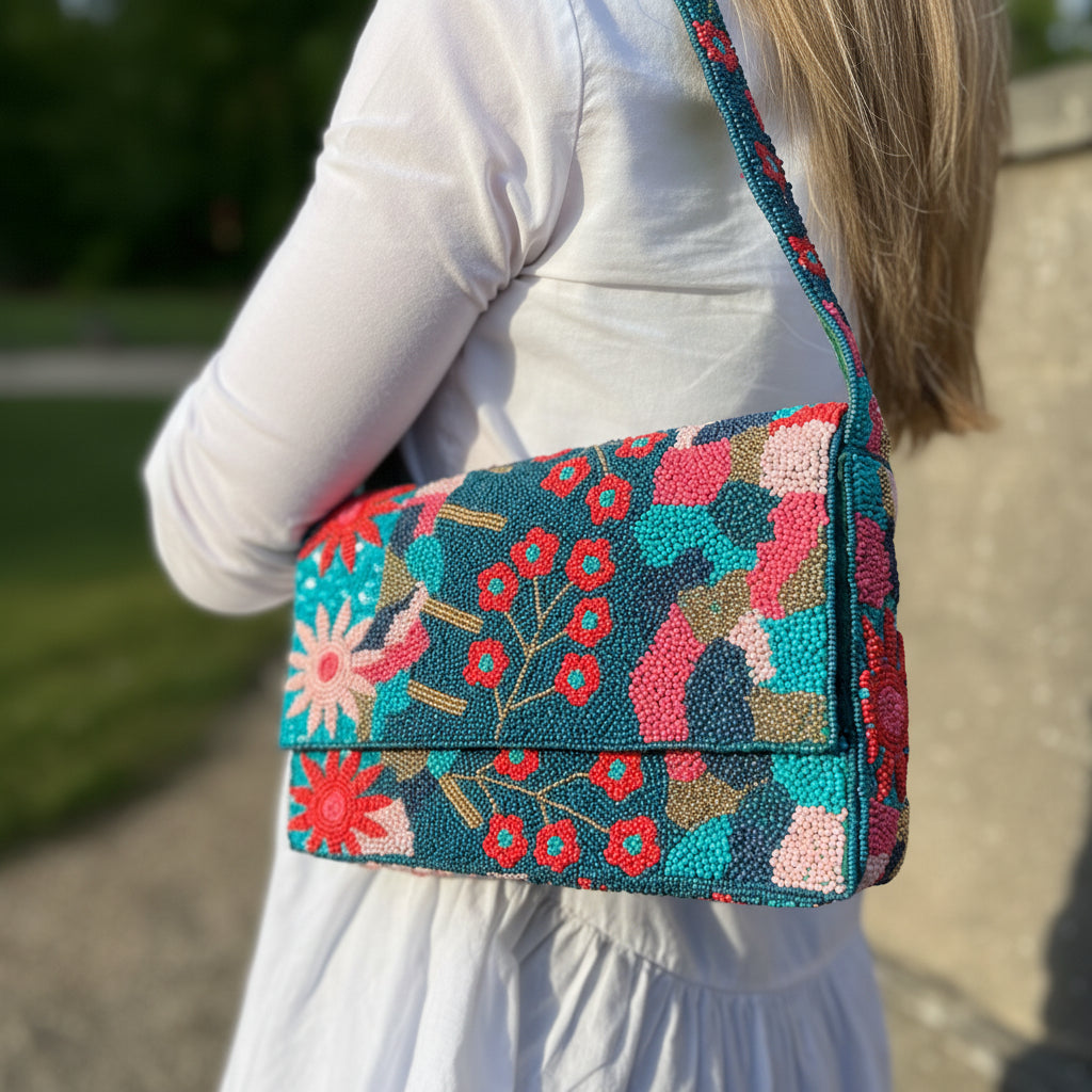 Teal beaded shoulder bag with pink florals worn on shoulder