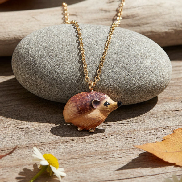Enamel hedgehog pendant necklace on grey stone with autumn leaves and daisy flower