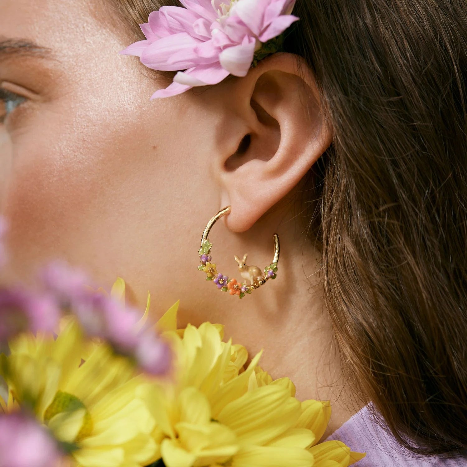 Model wearing Enamel Rabbit Hoop Earrings with hand-painted flowers and gold-plated hoops.