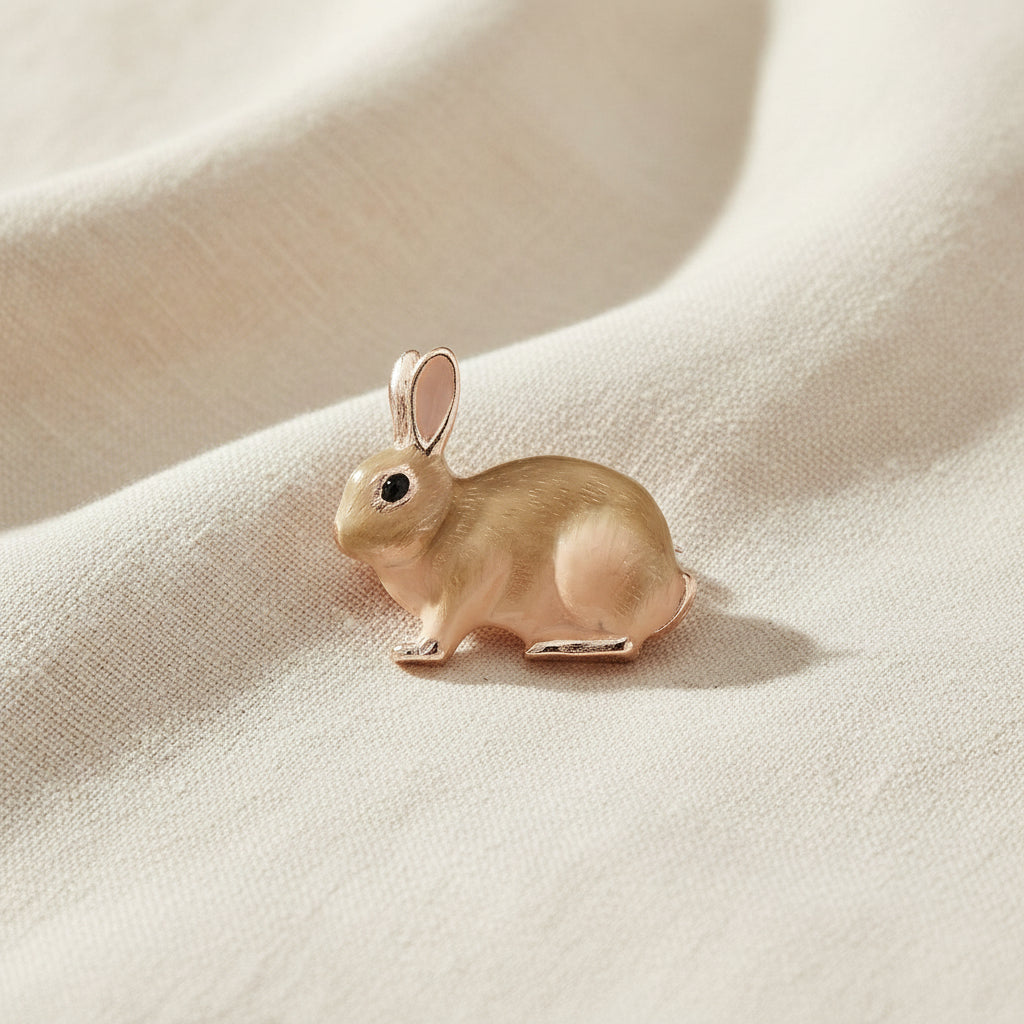 Enamel rabbit brooch in soft beige tones on cream linen fabric
