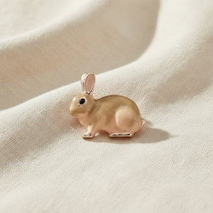 Enamel rabbit brooch in soft beige tones on cream linen fabric