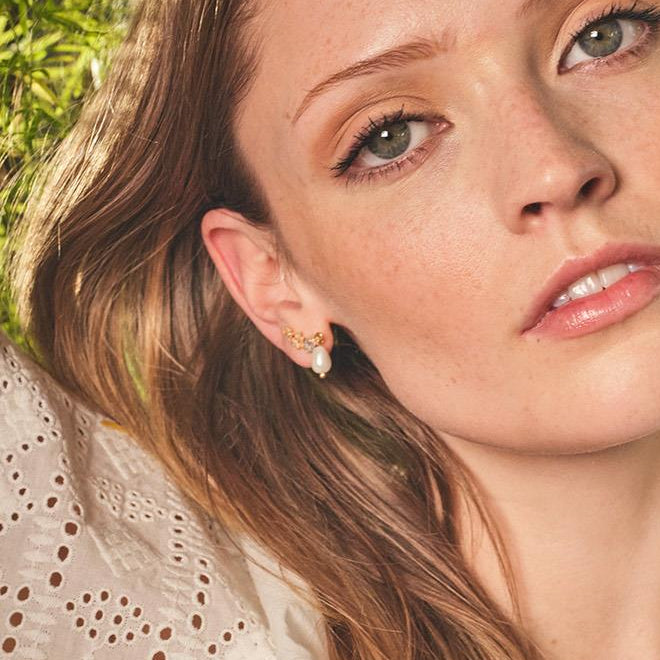 Hibiscus pearl earring worn on model in outdoor setting