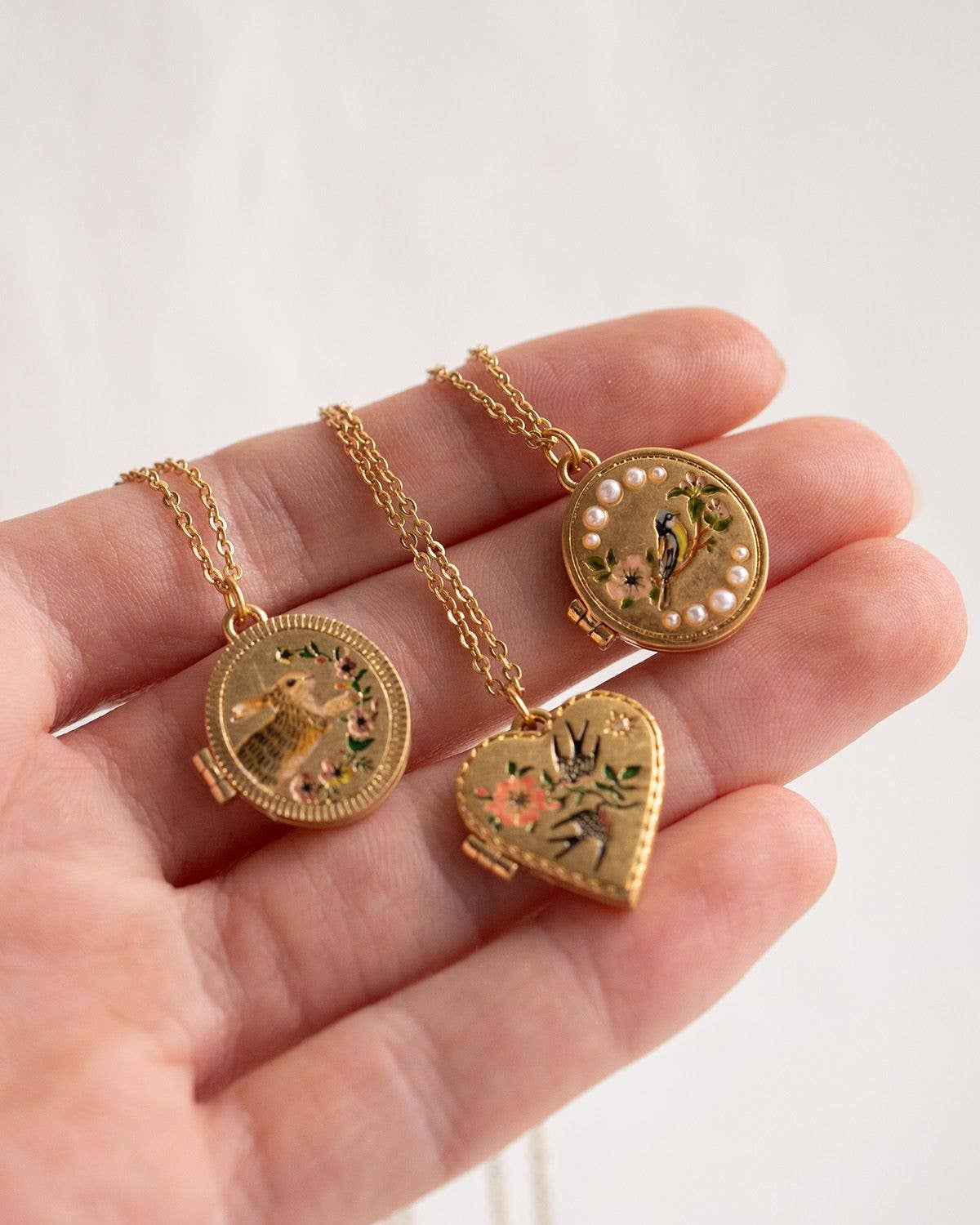 Three Fable England lockets including running bunny held in a hand