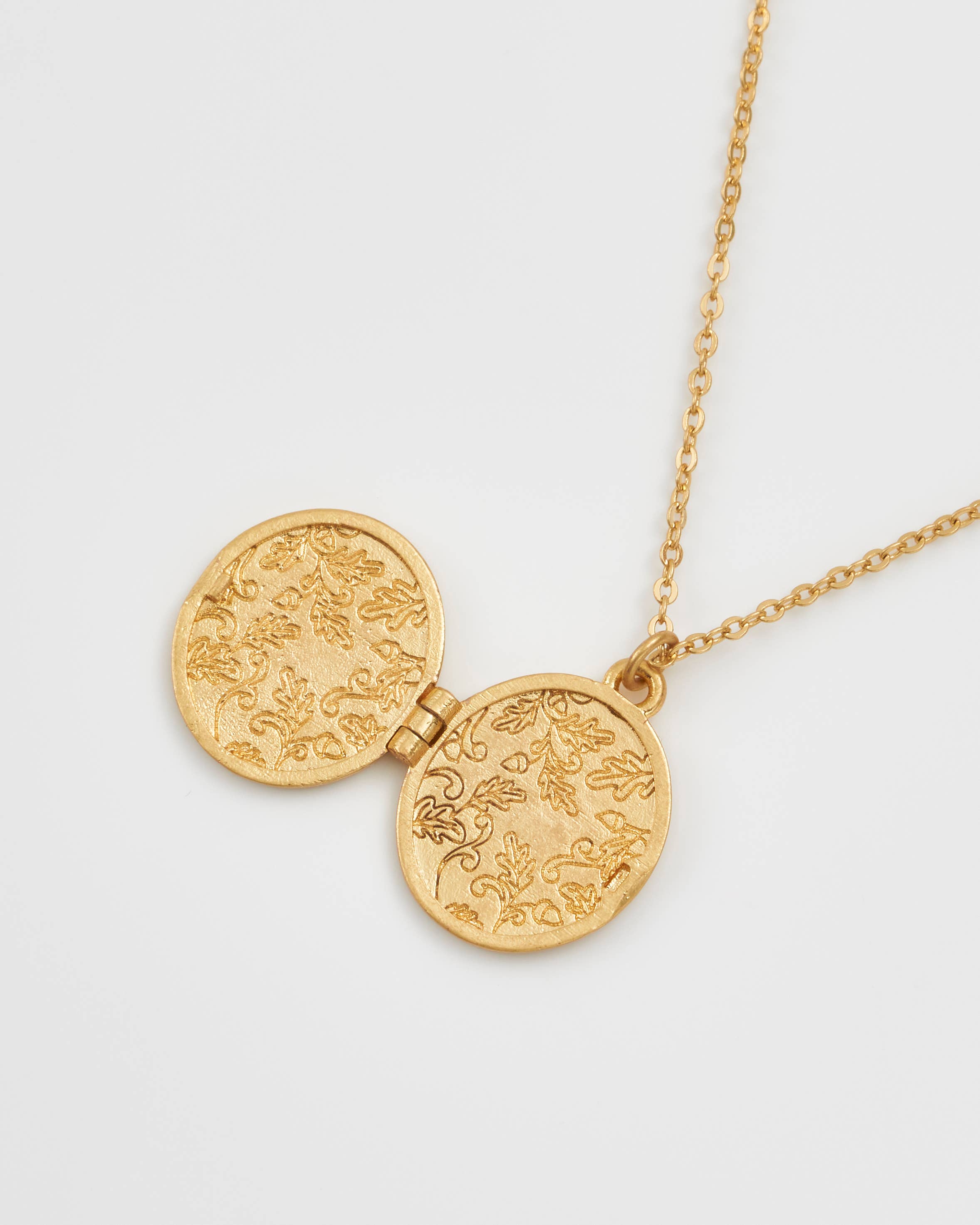 Running bunny locket open showing engraved oak leaf interior on white