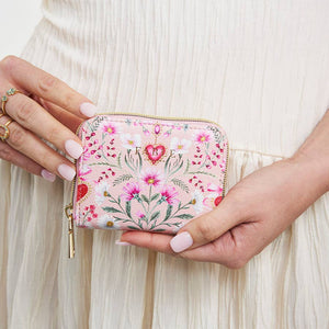 Person holding the floral heart pink purse in both hands.