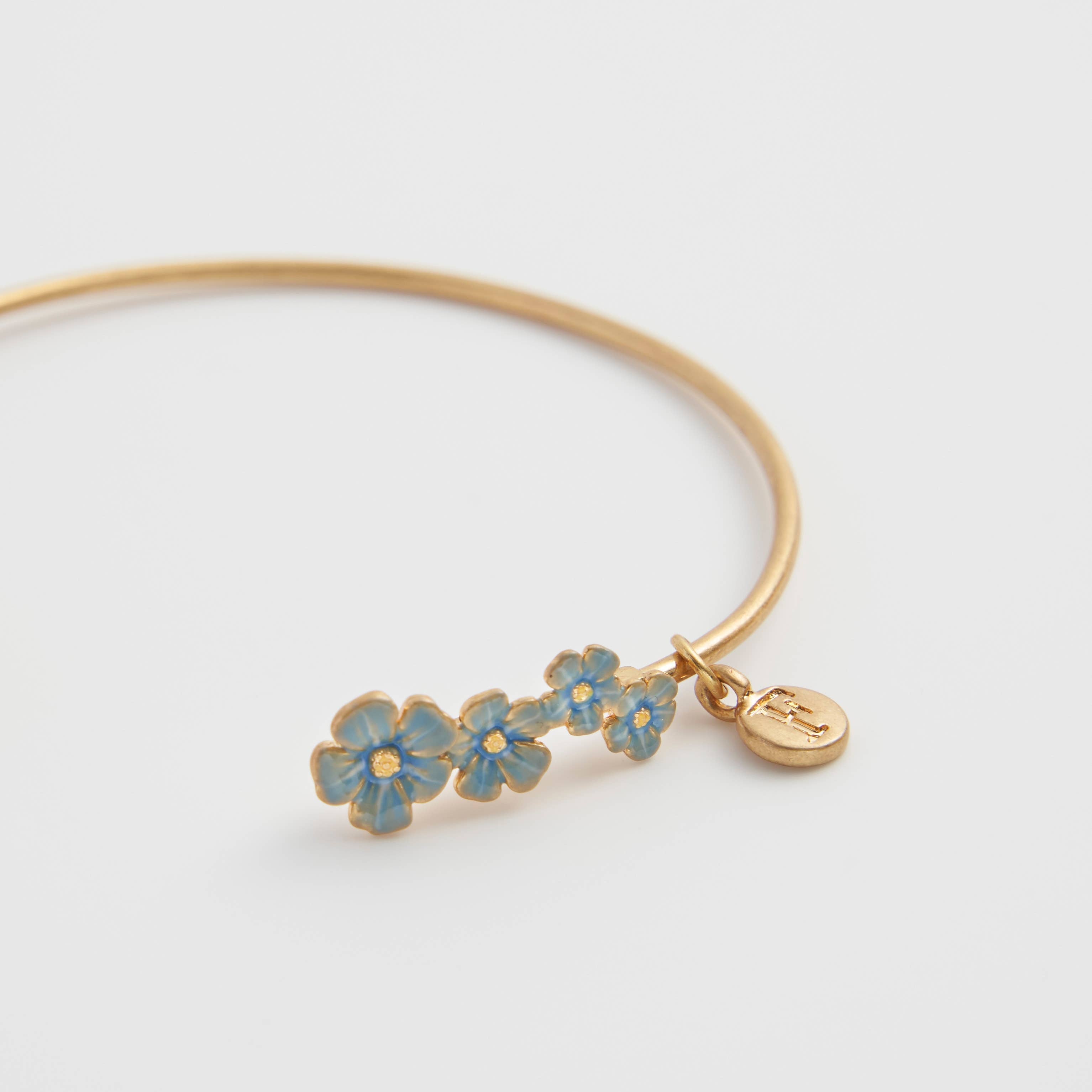 Close-up of forget-me-not bangle showing hand-painted enamel flowers and Fable charm