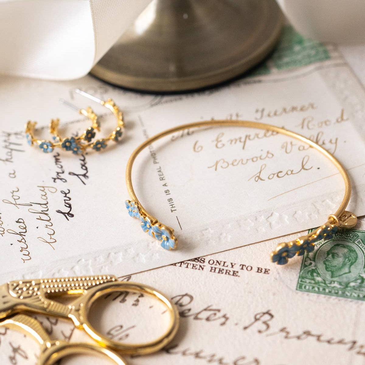Forget-me-not enamel bangle styled with vintage stationery and gold accessories