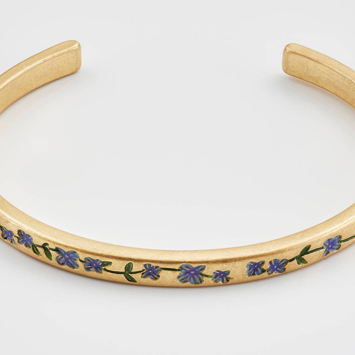 Detail close-up of gold bangle with blue enamel flowers