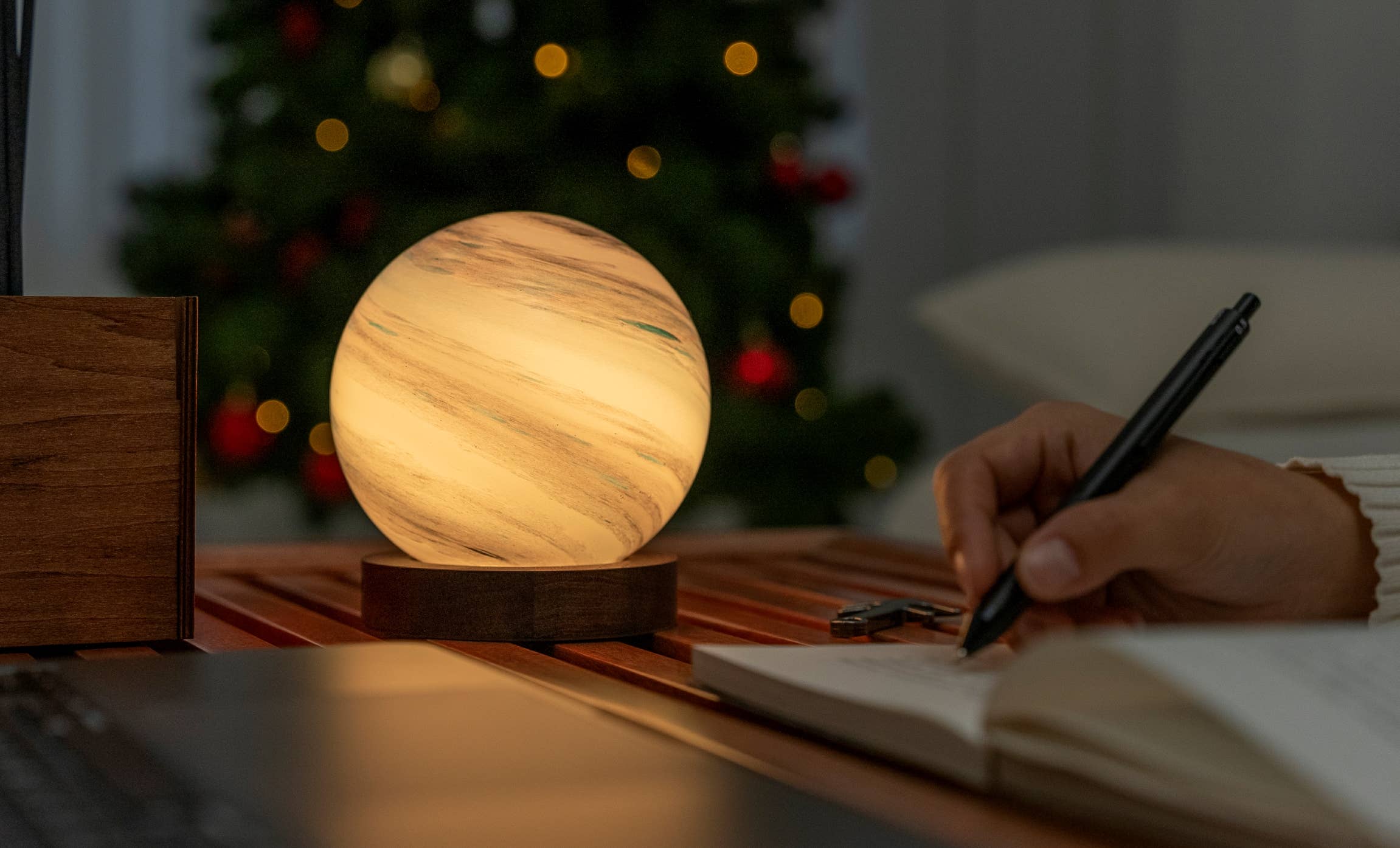 AstraGlass mini light in warm cream glow while someone writes nearby