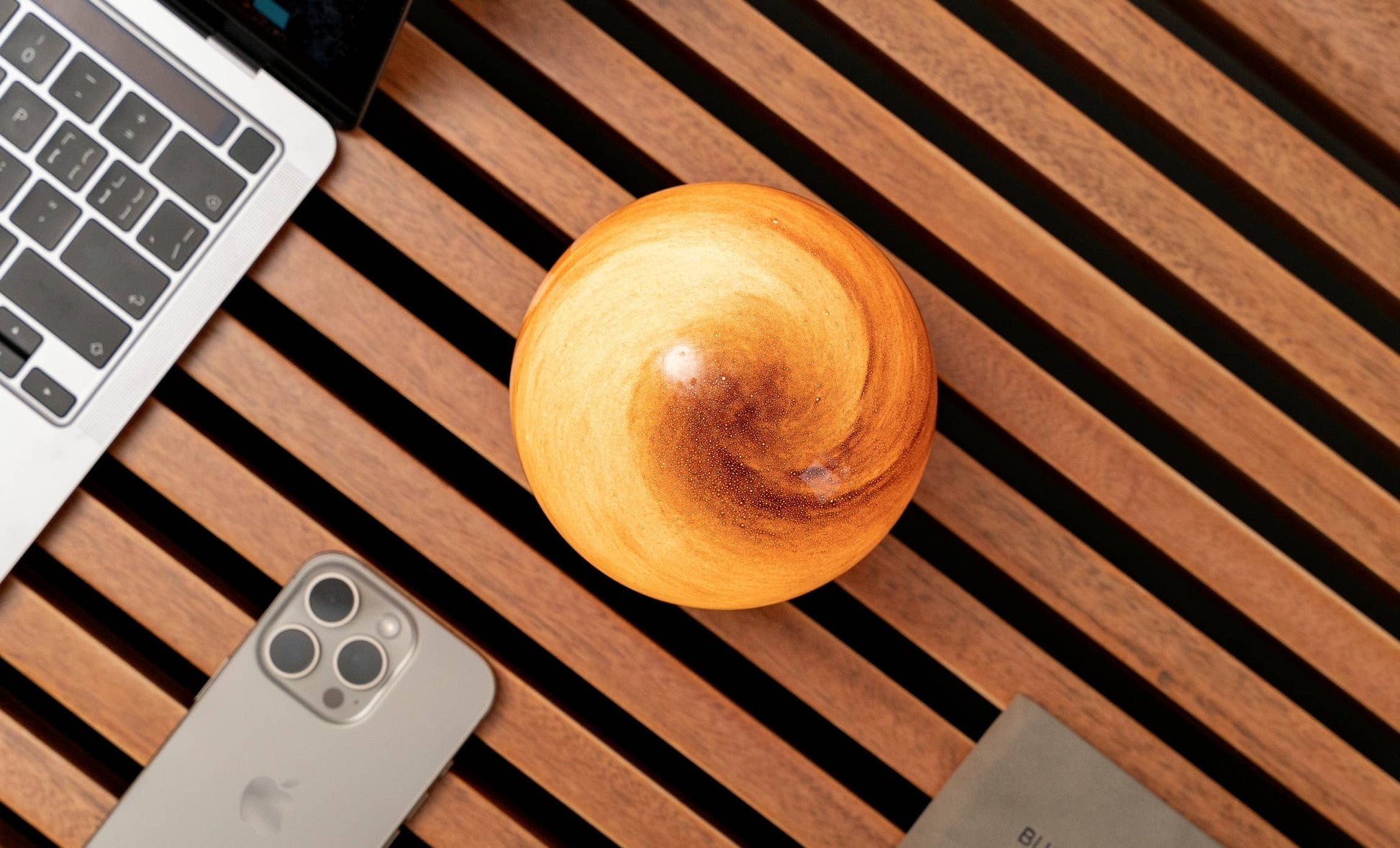 AstraGlass light overhead showing golden swirl finish beside phone