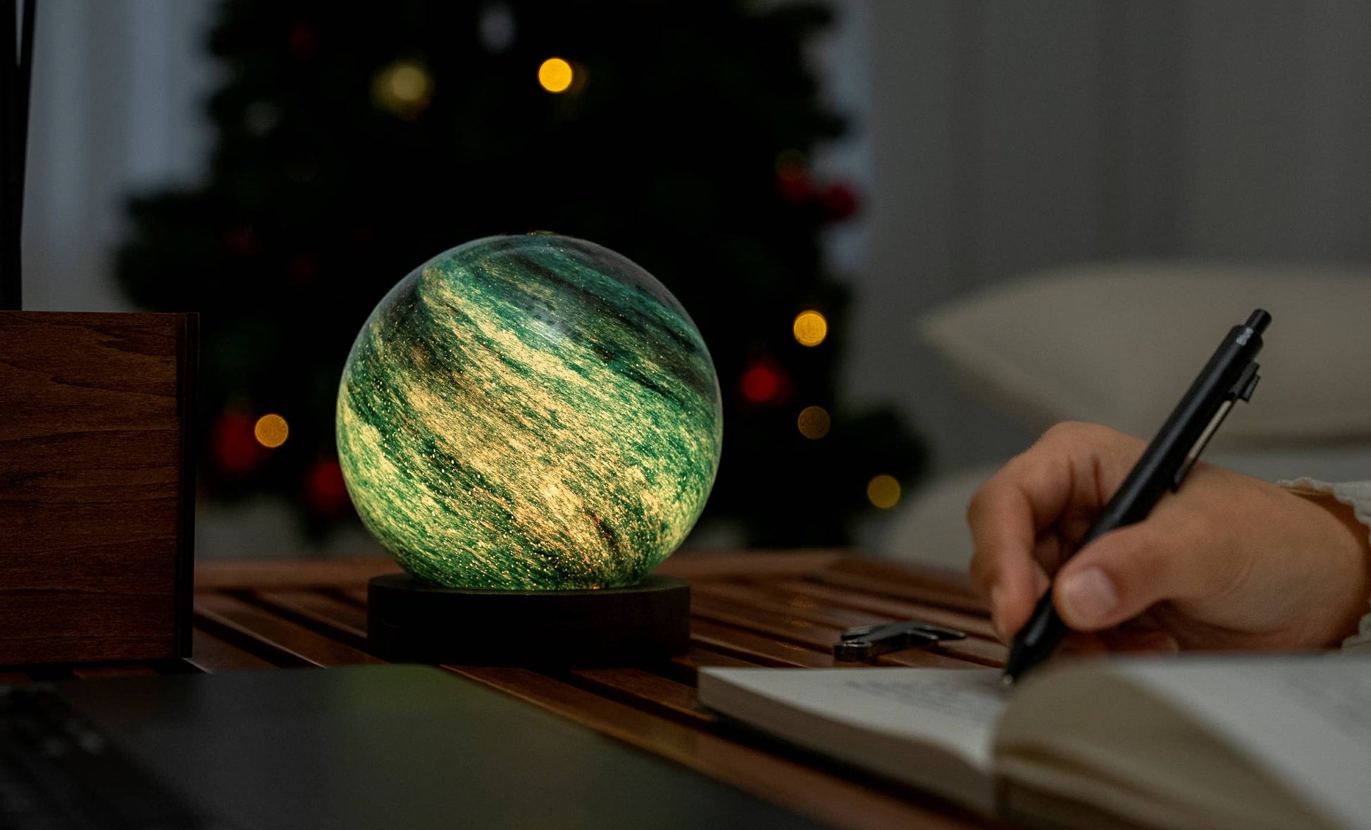 AstraGlass light in green glow on desk while someone writes notes