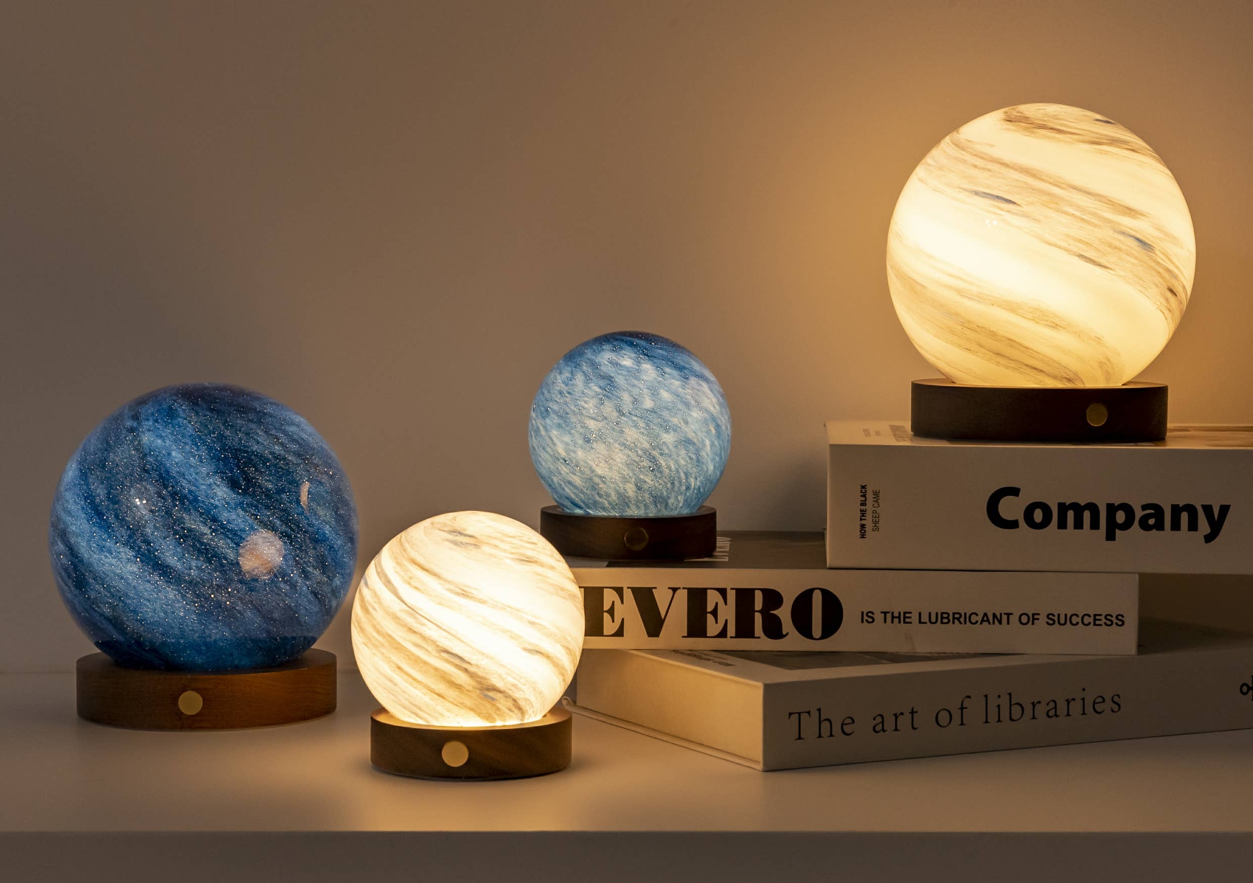 AstraGlass mini and large lights glowing beside stacked white books