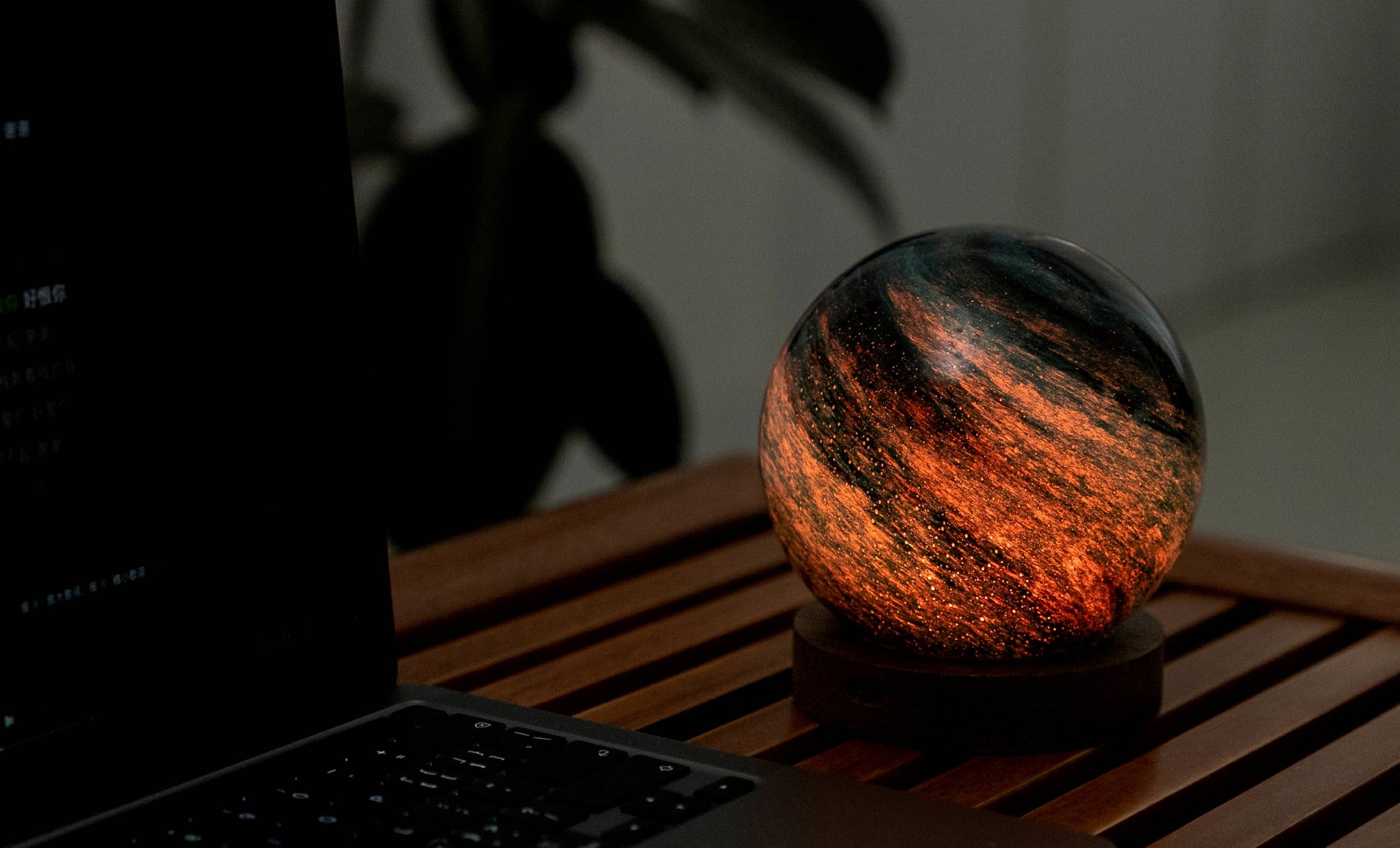AstraGlass orb glowing fiery orange and black on slatted table