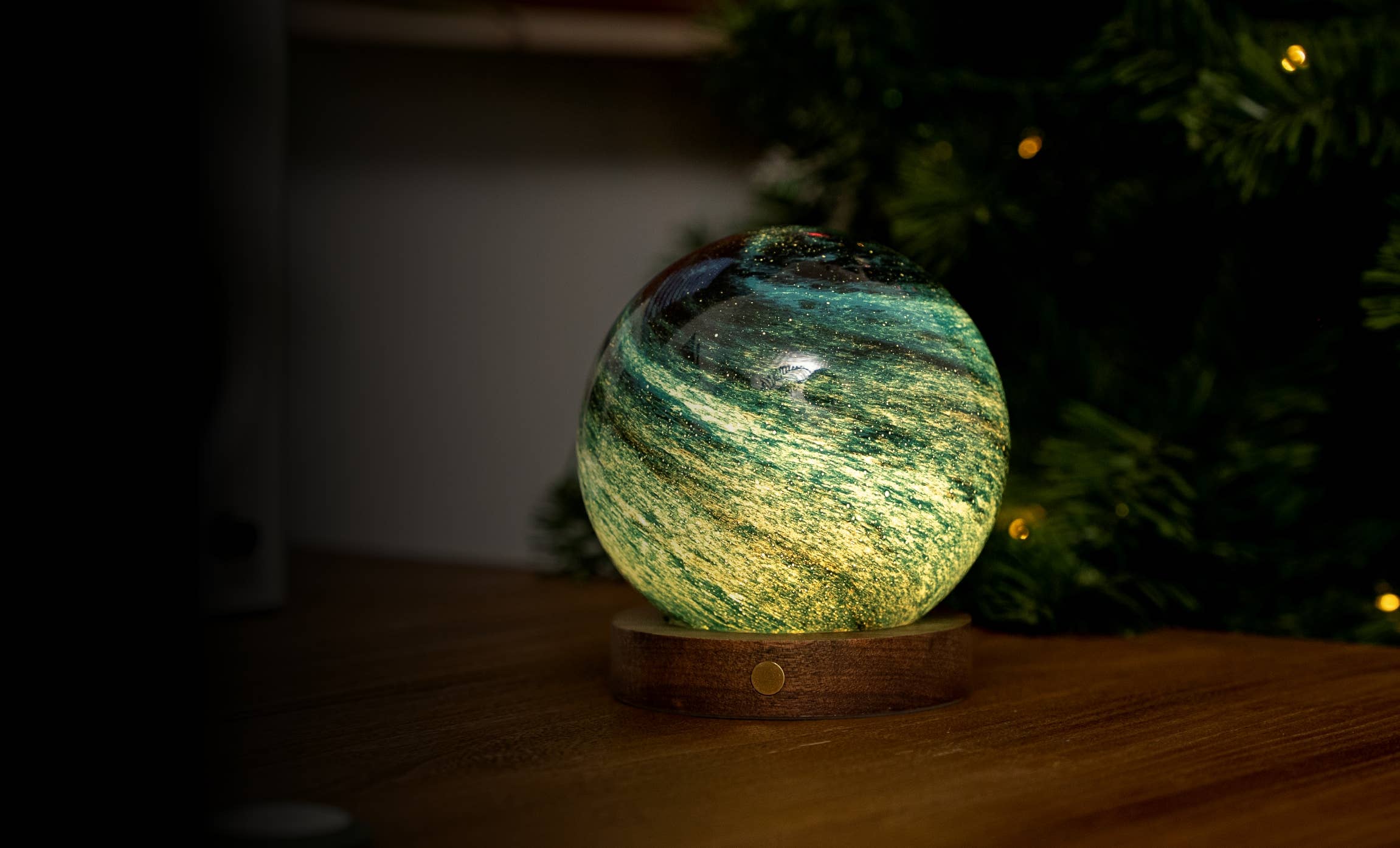 AstraGlass light glowing teal green beside a Christmas tree