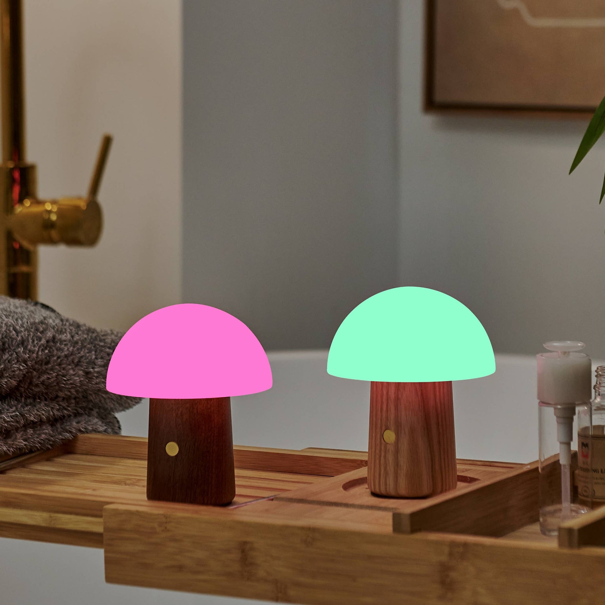 Alice mushroom lamps glowing pink and green on a bamboo bath tray