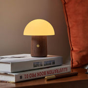 Mini Alice Mushroom Lamp in walnut glowing warm white on bedside books
