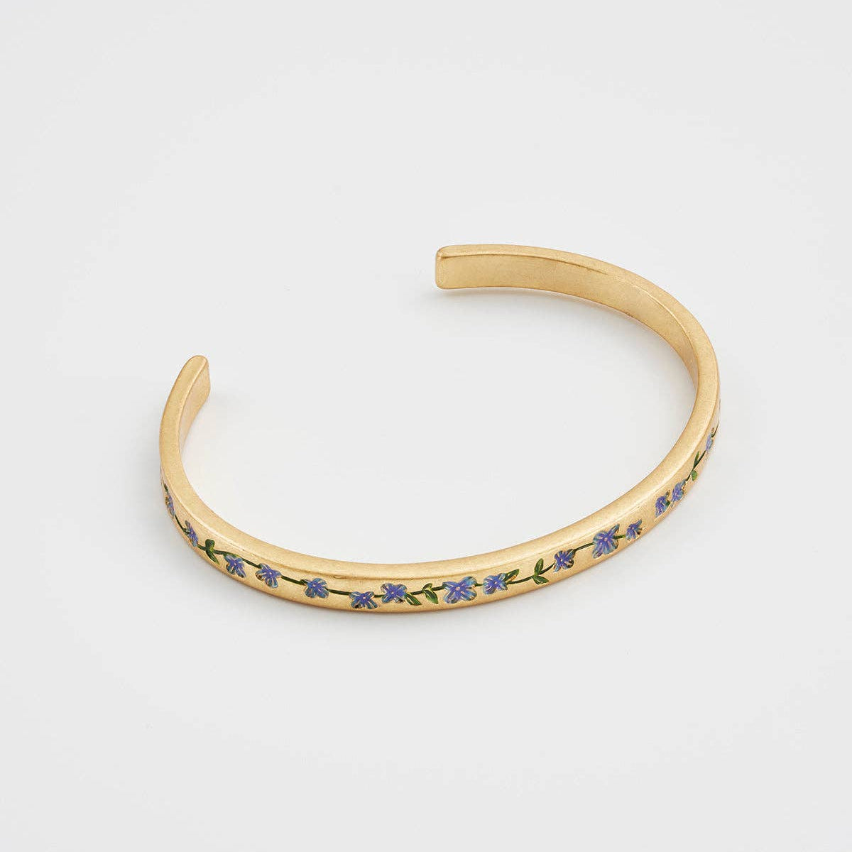 Side view of gold floral open-cuff bangle on white background