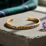 Gold forget me not bangle with blue floral detailing on white background