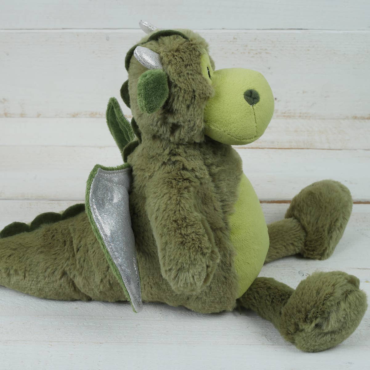 Side view of green dragon plush soft toy showing silver wings and soft textured fur
